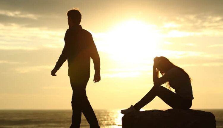 Couple silhouette breaking up a relation on the beach at sunset